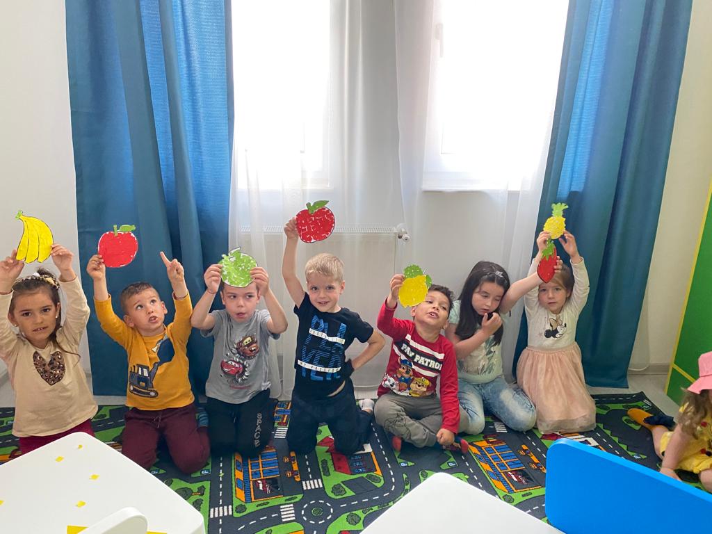 Seven kids lined up showing their cardbord fruits