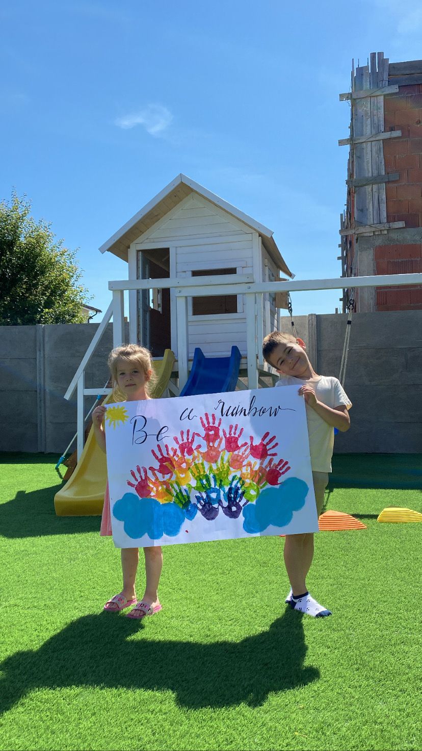 Two kids holind on to a poster with colorful painted hands