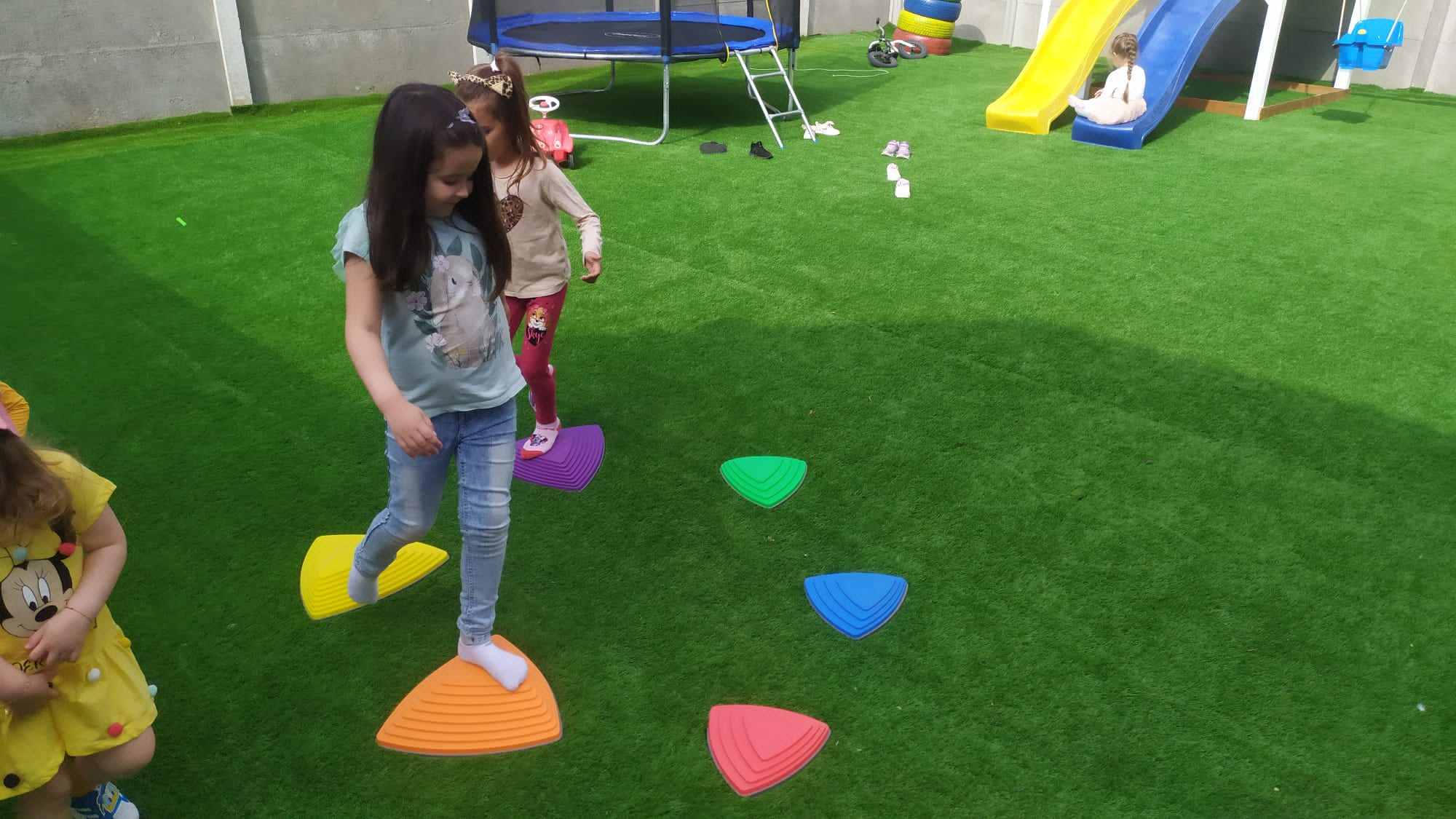 Kids in the garden, stepping on colorful plastic stones