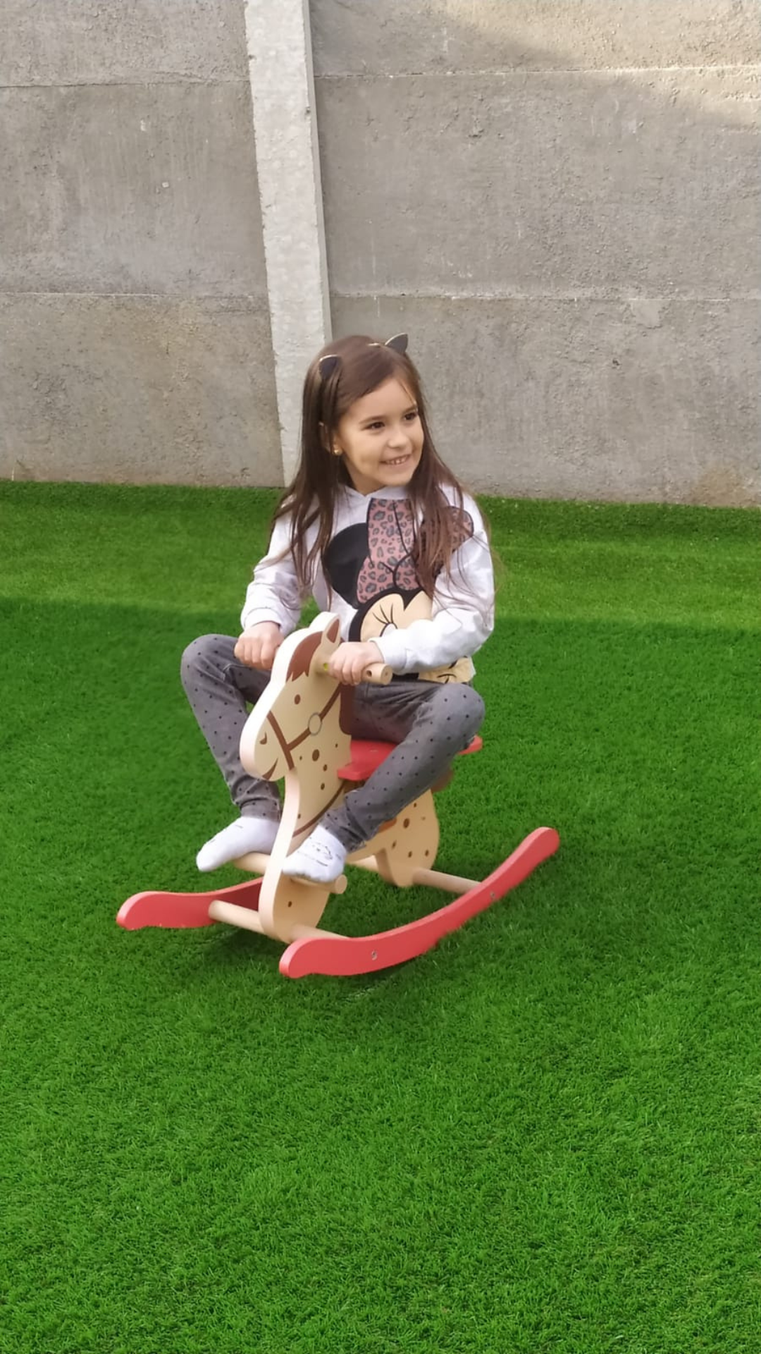 A little girl on a wooden horse toy