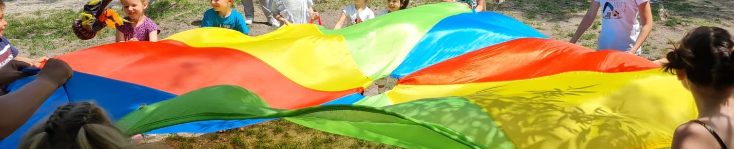 kids standing in a circle holding a rainbow scarf