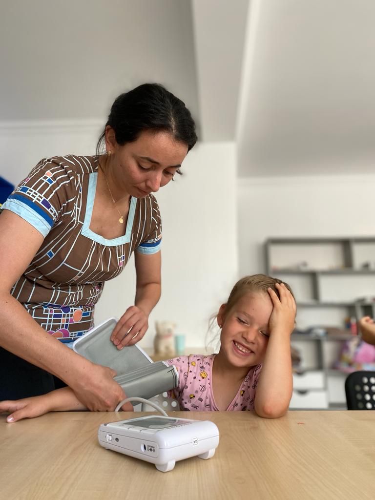 A nurse showing a kid how to test the blood pressure