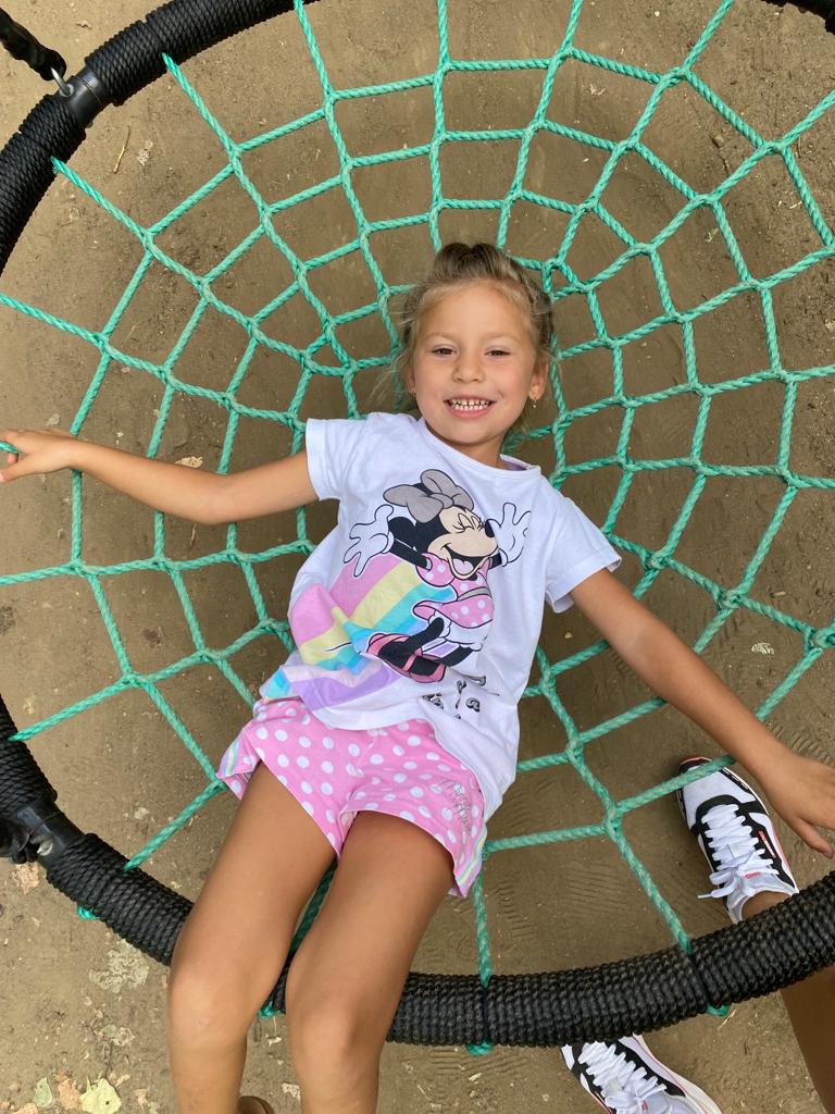 A little girl laying on a knitted swing