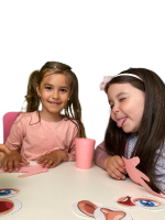 Two girls sitting at a table, sticking their tongues out